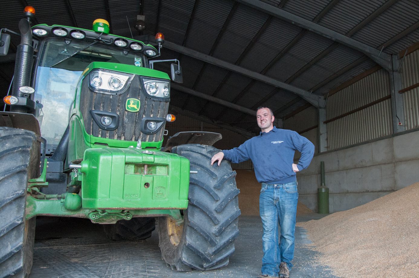a man standing next to a large green tractor